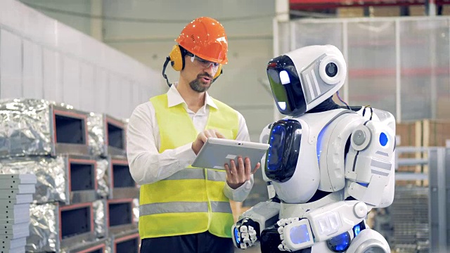 詳情圖-男性工人與機器人交談，在平板電腦上向機器人顯示信息，然后在機器人的顯示器上輸入信息。4,k。