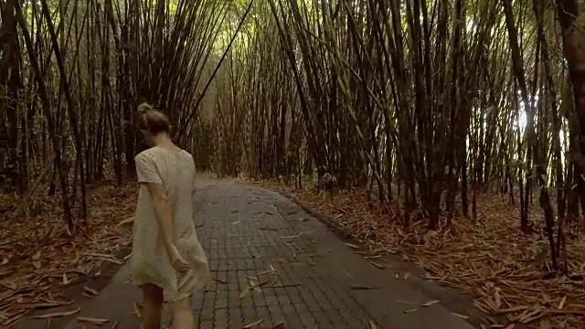 在竹林中沉思大自然的快乐年轻女子的慢动作
