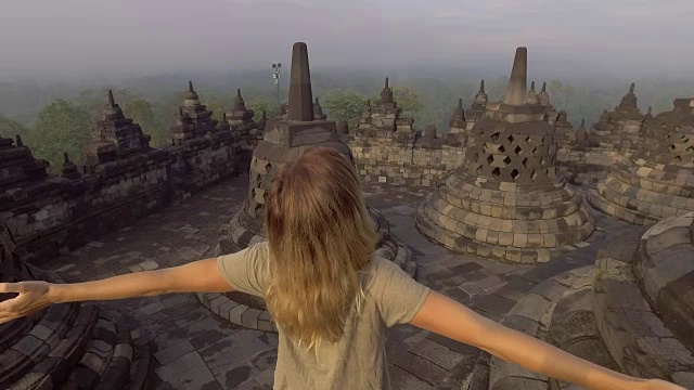 4K分辨率的视频旅行女孩拥抱日出在婆罗浮屠寺，印度尼西亚。People discovery Asia概念
