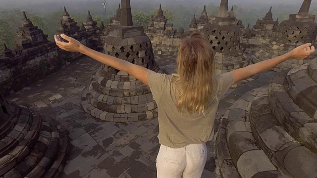 4K分辨率的视频旅行女孩拥抱日出在婆罗浮屠寺，印度尼西亚。People discovery Asia概念