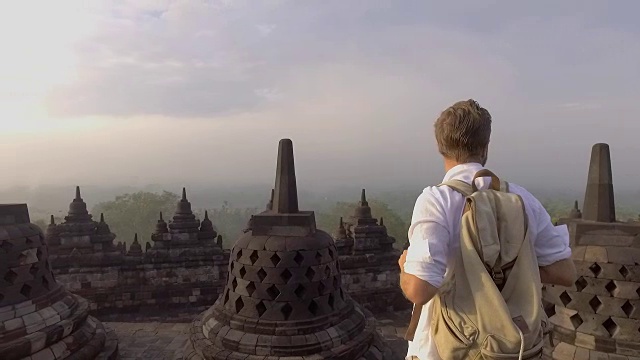 印尼婆罗浮屠寺，一名男子凝视日出的慢动作视频。人们旅行冒险的概念