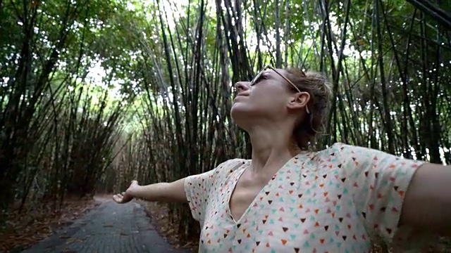 年轻女子在竹林中伸开双臂，享受大自然中的自由4K视频