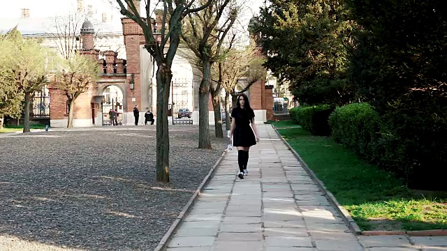 一个女孩走在一个大学附近的滑板上的大学背景