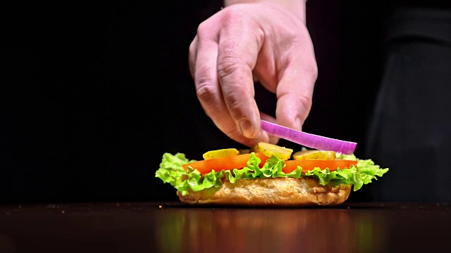 汉堡是在黑色的背景和黑色的食品手套烹饪。非常美味的空气面包和大理石牛肉。每个汉堡都是手工制作的餐厅。没有理想。看起来是真实的，充满爱意的手工制作。
