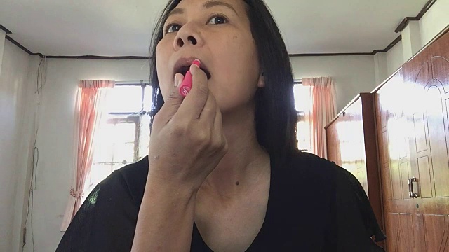 在嘴唇上涂红色口红的女人