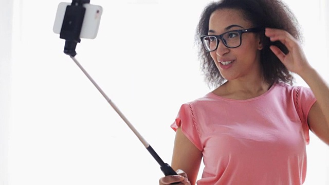 在家用自拍杆用智能手机拍照的女人