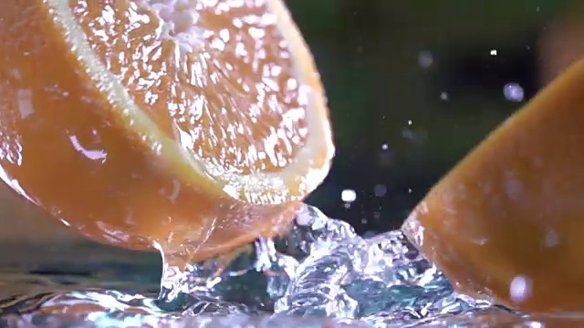 橙子碰到橙汁表面，切成两半。慢动作镜头。近距离