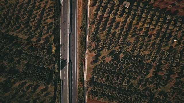 从上面的视频中可以看到日落时分在乡村道路上行驶的汽车的鸟瞰图。