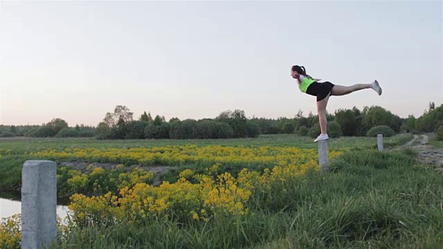 一个目的明确的女人单腿站着做瑜伽练习。那个女孩在日落时正在做运动