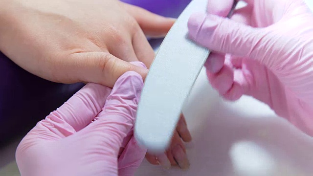 近距离的美容师锉指甲的顾客在美容院