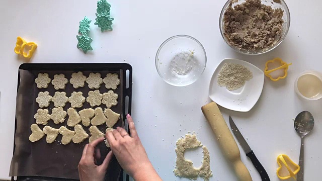 女人酥饼饼。将面团揉匀，撒上芝麻粒。用模具成型，用图章应用图案。间隔拍摄。