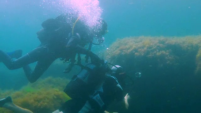 詳情圖-一名男性游客帶著相機(jī)在水下潛水，教練扶著他在水下