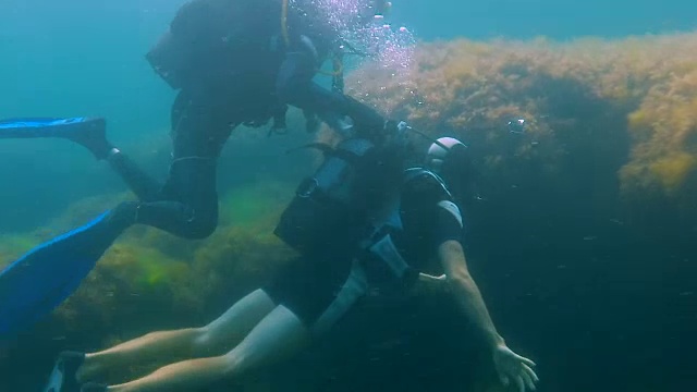 詳情圖-一名男性游客帶著相機(jī)在水下潛水，教練扶著他在水下