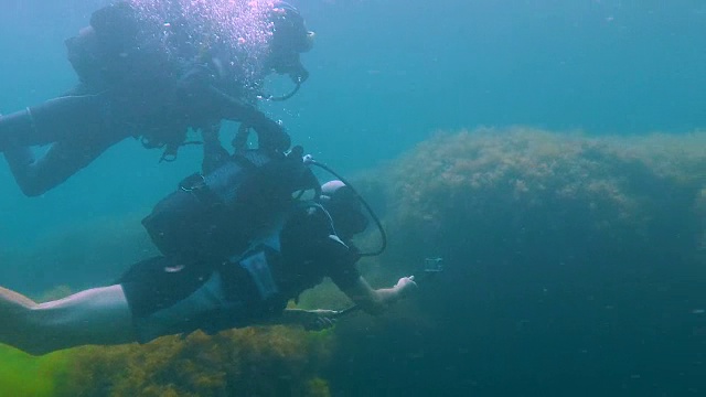 詳情圖-一名男性游客帶著相機(jī)在水下潛水，教練扶著他在水下