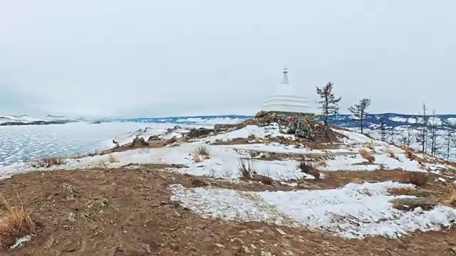 女人在贝加尔湖冰面上的旅行。观点的看法。闭关独特的佛塔布尔可汗纪念碑象征神秘的历史仪式岛大井山水山萨满教崇拜。冬岛之旅。