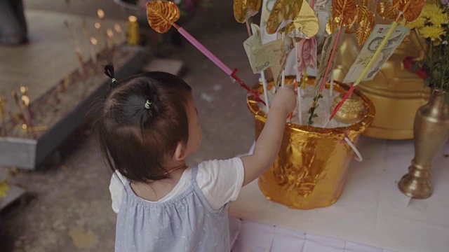 亚洲可爱的女婴是花时间祈祷和做功德。