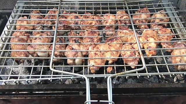 在烧烤架上翻过来的鸡翅。肉在Mangal烧烤架上炸。鸡肉上的女孩