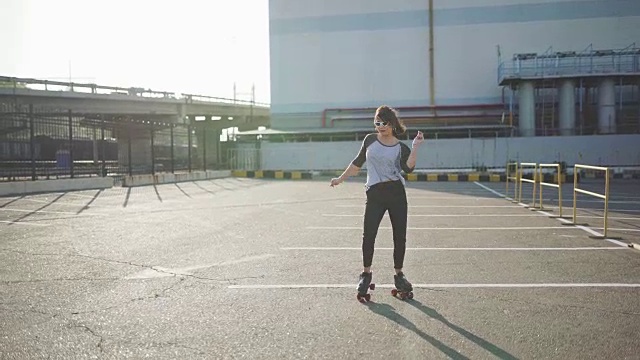 漂亮迷人的年轻女子在街上滑旱冰和跳舞。城市背景