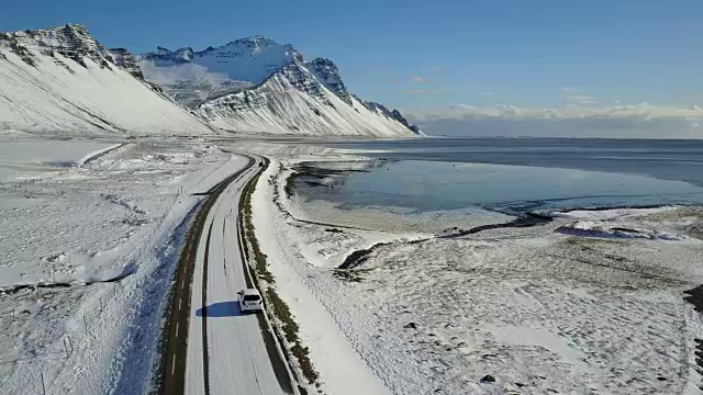 在冰岛东海岸的冬季，飞过冰雪覆盖的道路和雪山景观