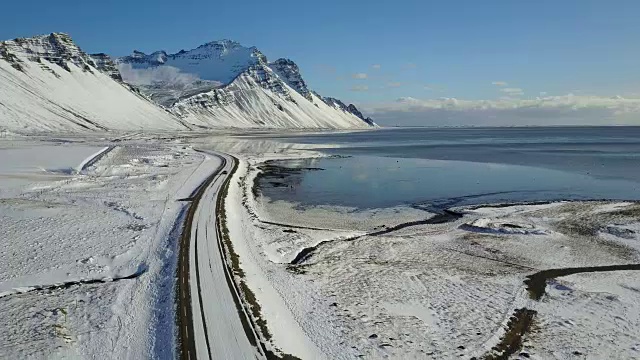 在冰岛东海岸的冬季，飞过冰雪覆盖的道路和雪山景观