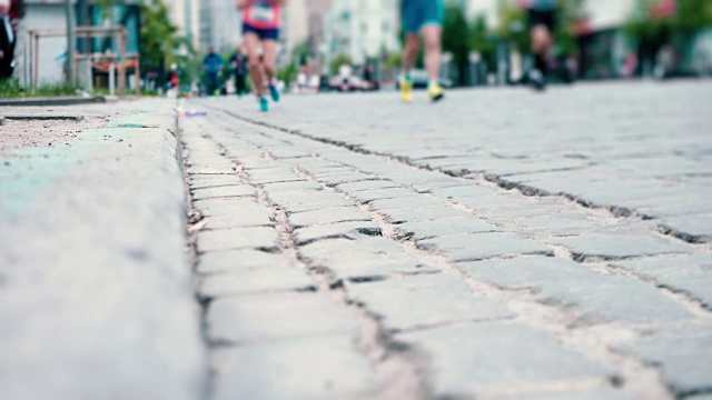 运动员沿着铺有石子的道路跑步，城市马拉松，运动员的双腿特写，体育竞赛