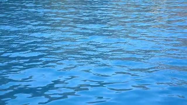 游泳池或海中的蓝色清澈的水潭。美丽的水纹理背景。特写慢动作