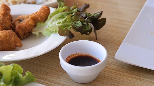 孩子的手把酥脆的鸡腿放进酱汁里吃。