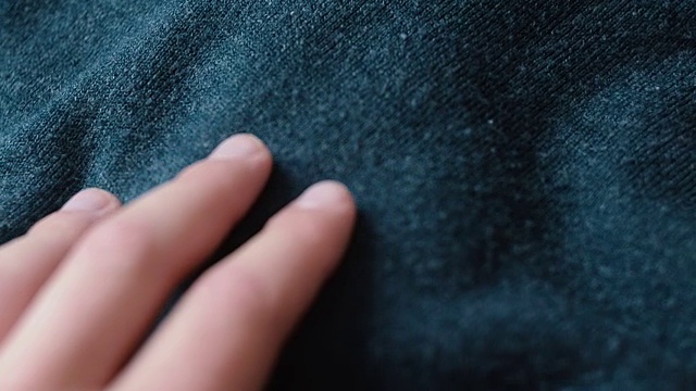 一名男子在纺织厂触摸光滑的蓝色腈纶织物