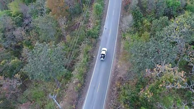空中拍摄的汽车驾驶通过森林道路无人机旅行乡村冒险