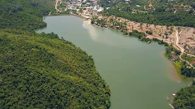 详情图-鸟瞰图绿色湖泊和大坝的背景山丘和山脉覆盖的热带森林。无人机飞越河流与大坝和岩石岸线在山区