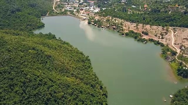 详情图-鸟瞰图绿色湖泊和大坝的背景山丘和山脉覆盖的热带森林。无人机飞越河流与大坝和岩石岸线在山区