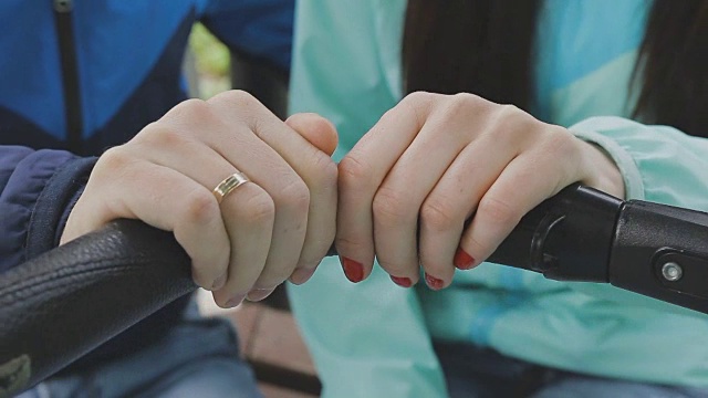 一对夫妇推着婴儿车在公园里散步聊天