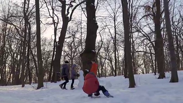 孩子们在冬季公园堆雪人，慢镜头