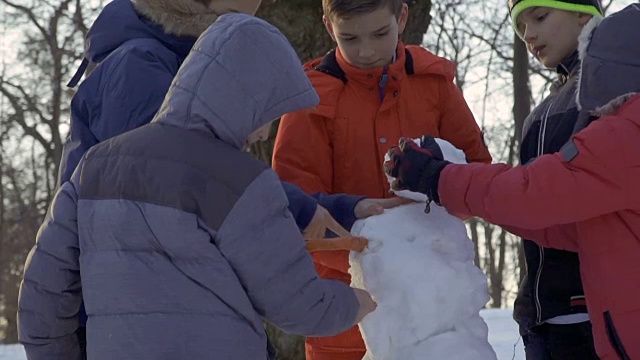 五个男孩在冬季公园堆雪人