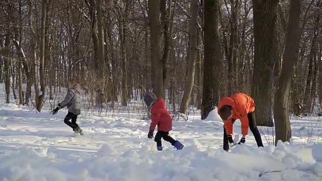 三兄弟在冬季公园玩雪球，慢镜头