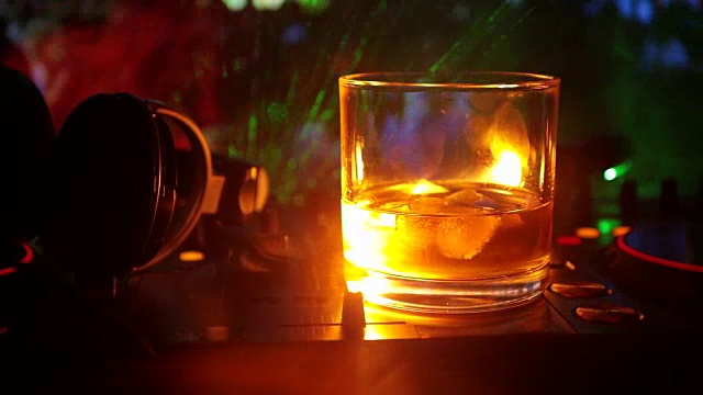 詳情圖-在夜總會(huì)的dj控制器上，裝有冰塊的威士忌酒杯。在迪斯科燈光下的夜總會(huì)音樂派對上，一杯威士忌上戴著Dj耳機(jī)?；瑝K拍攝