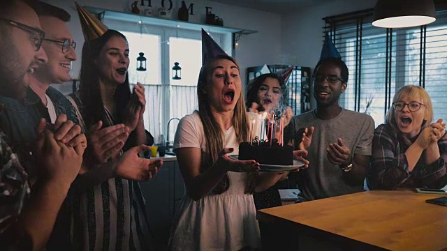 詳情圖-快樂的歐洲女孩拿著生日蛋糕，許愿和吹，多民族的朋友唱歌在有趣的派對慢鏡頭