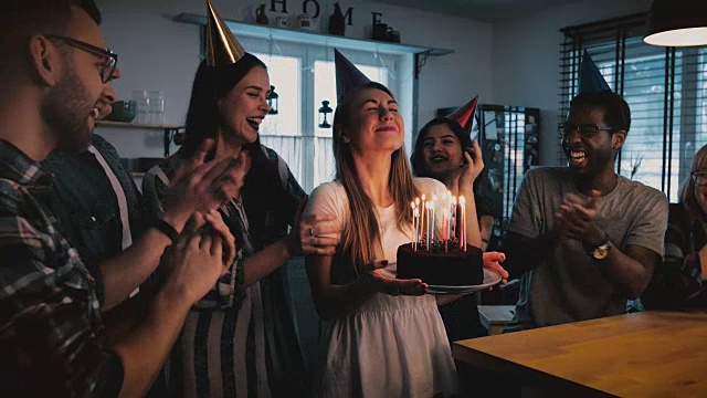 詳情圖-快樂的歐洲女孩拿著生日蛋糕，許愿和吹，多民族的朋友唱歌在有趣的派對慢鏡頭