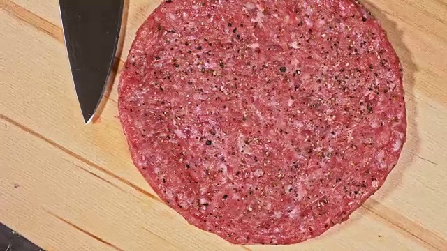 厨师为汉堡制作肉奖章。戴着黑色食品手套的厨师做肉排。在一个均匀的大奖章上，排骨被平放在钢环中。有大理石花纹的牛肉放在食物木板上。