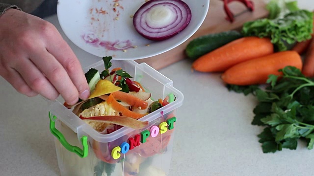 人们把食物垃圾放进厨房的堆肥桶里
