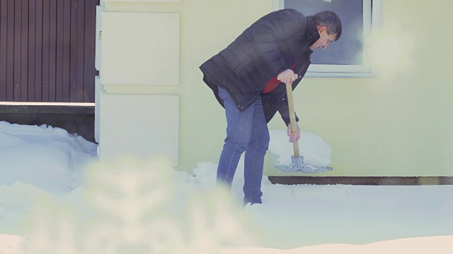 有人用铁锹清理房子附近的雪