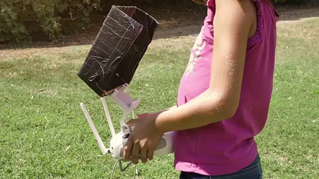 年轻的小女孩驾驶着无人机在夏季户外的绿草地上玩耍遥控飞行员慢动作