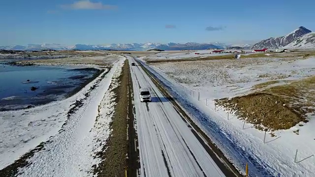 在冰岛东海岸的冬季，飞过冰雪覆盖的道路和雪山景观