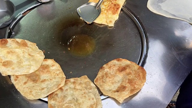 在泰国的市场上做异国风味的泰国煎饼，马来西亚烤饼。用煮熟的油在热的金属锅上煎蛋。泰国小吃。泰国甜点。