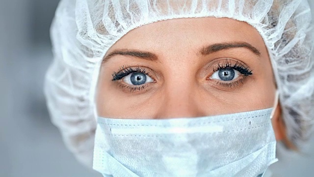在医院或实验室里戴着外科口罩，背景模糊的医护人员或科学家