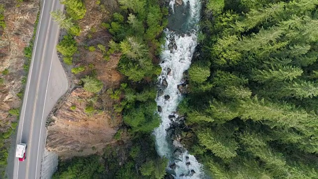 野营卡车在公路旅行冒险驾驶沿着路边悬崖愤怒河森林自上而下鸟瞰图