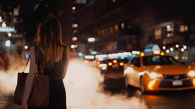 年轻美丽的女人站在交通道路在晚上，纽约市中心，美国