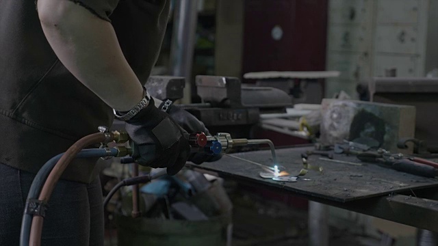 近距离的妇女焊接工焊接两件金属在她的车间