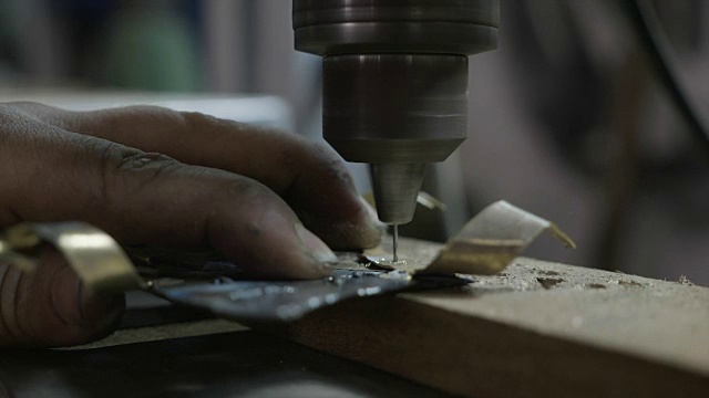 近距离的妇女铁匠或焊接工的手拿着和在她的diy车间钻一块金属