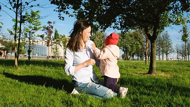 女人和孩子在大自然中玩耍。快乐的妈妈挠着草叶孩子的脸